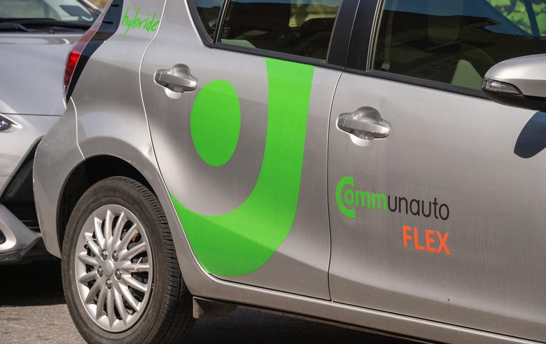Vue d'une voiture de la flotte de Communauto FLEX, avec un logo vert distinctif sur la portière. Le véhicule est garé et prêt à être utilisé dans le cadre du service de partage de voitures.