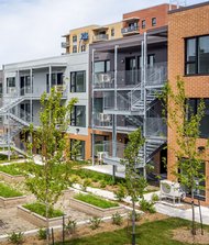 Cour intérieure verdoyante entre deux immeubles résidentiels à faible hauteur, avec escaliers métalliques, allées, bancs et bacs de plantation.